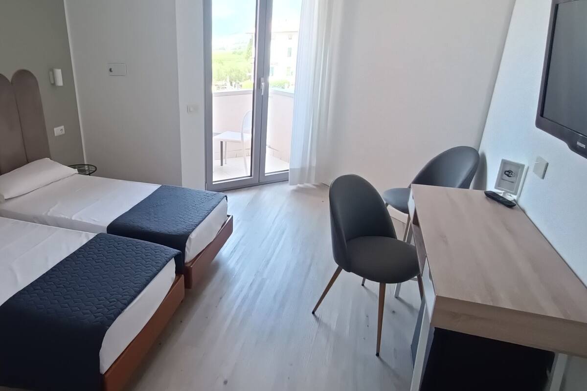 Une chambre d’hôtel avec deux lits, un bureau, une chaise et un téléviseur.