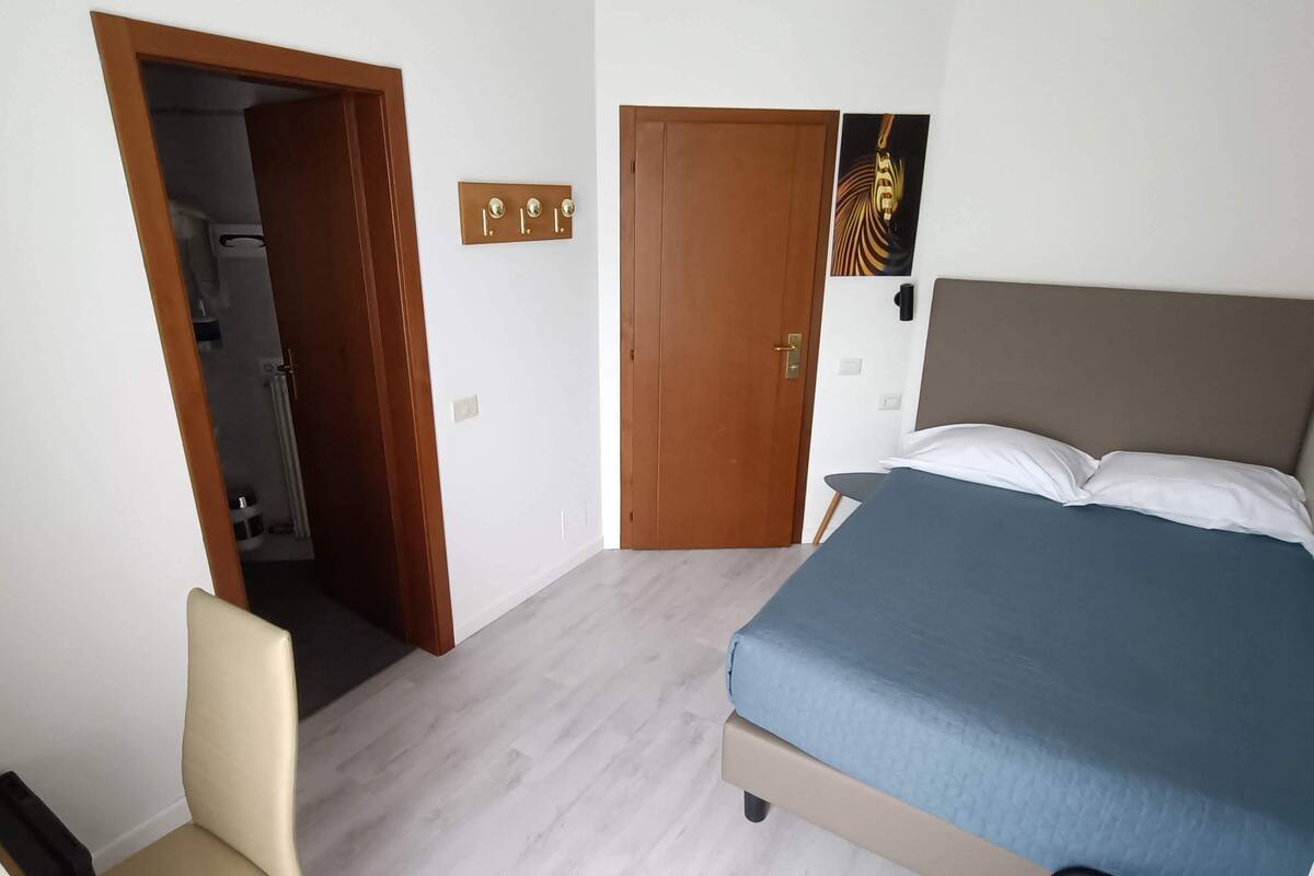 Une chambre avec un lit, une porte, un porte-serviettes et une petite table.