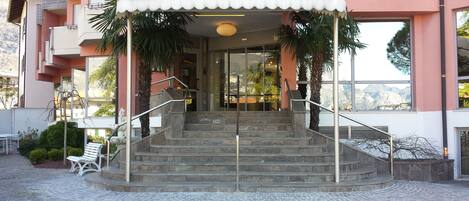 Un edificio con un acceso cubierto, una escalera que lleva a la entrada y vistas de montañas a través de las ventanas.