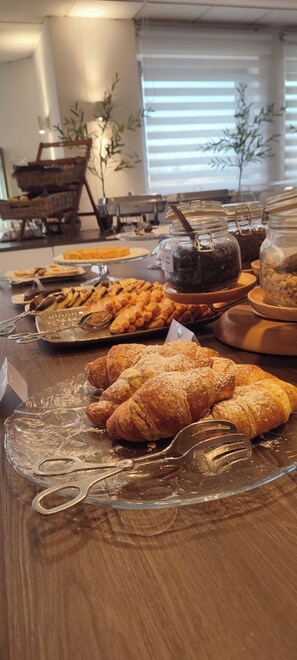 Una mesa de buffet con diversos pasteles y platos, entre ellos cruasanes y crema de chocolate.