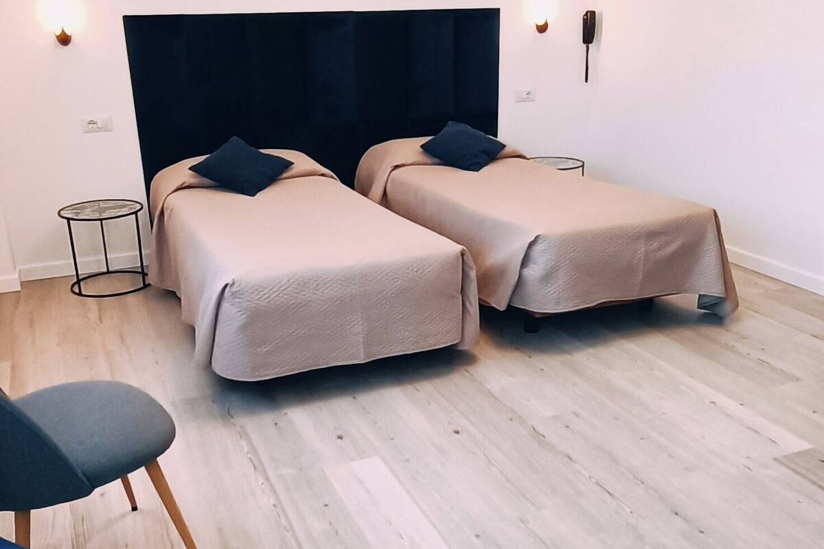 Une chambre d’hôtel avec deux lits, un canapé, une table ronde et un lustre moderne.