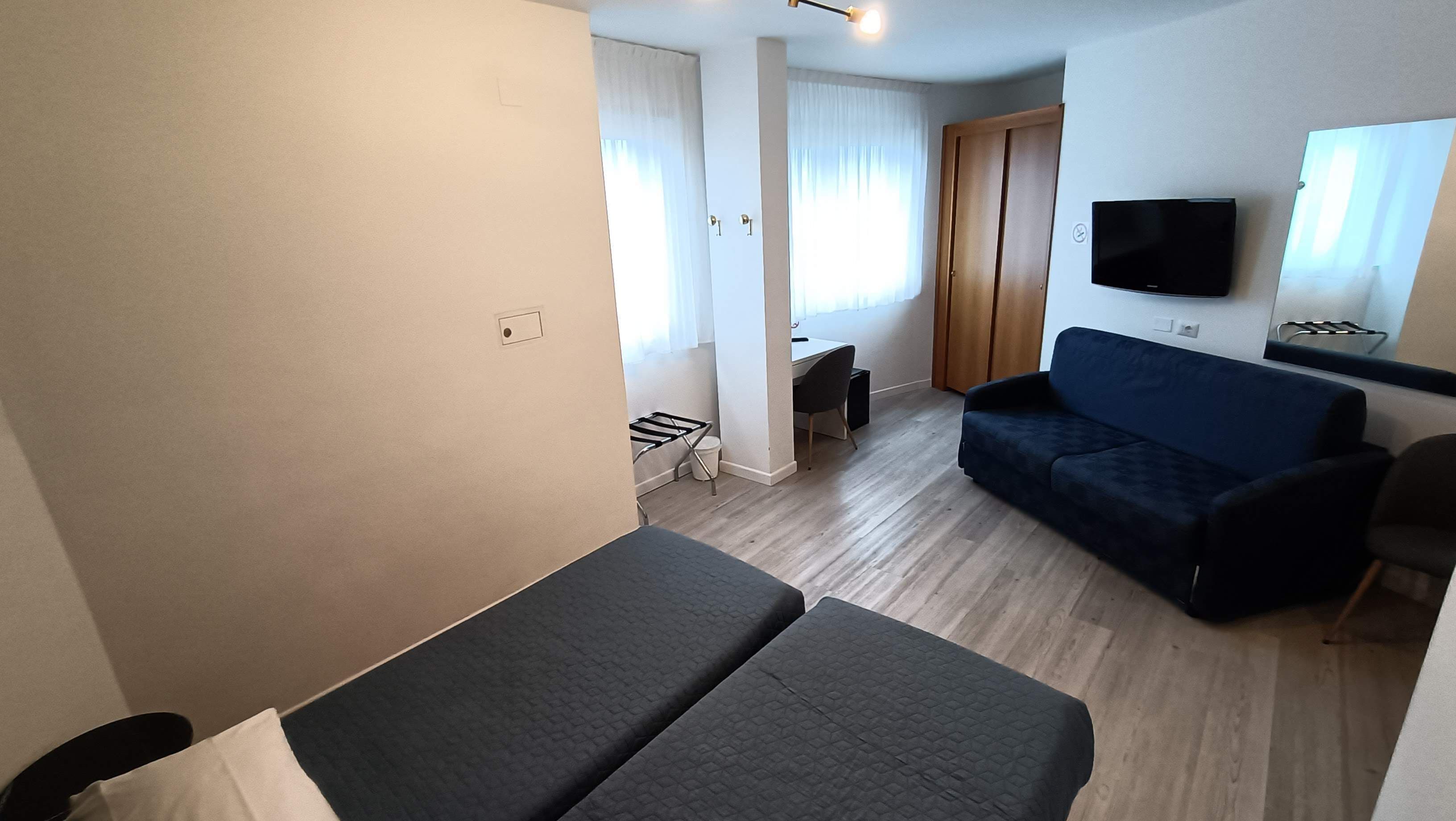 A room with a bed, a sofa, a TV, and a desk.