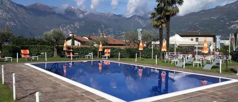 Una piscina al aire libre, sillones reclinables de piscina