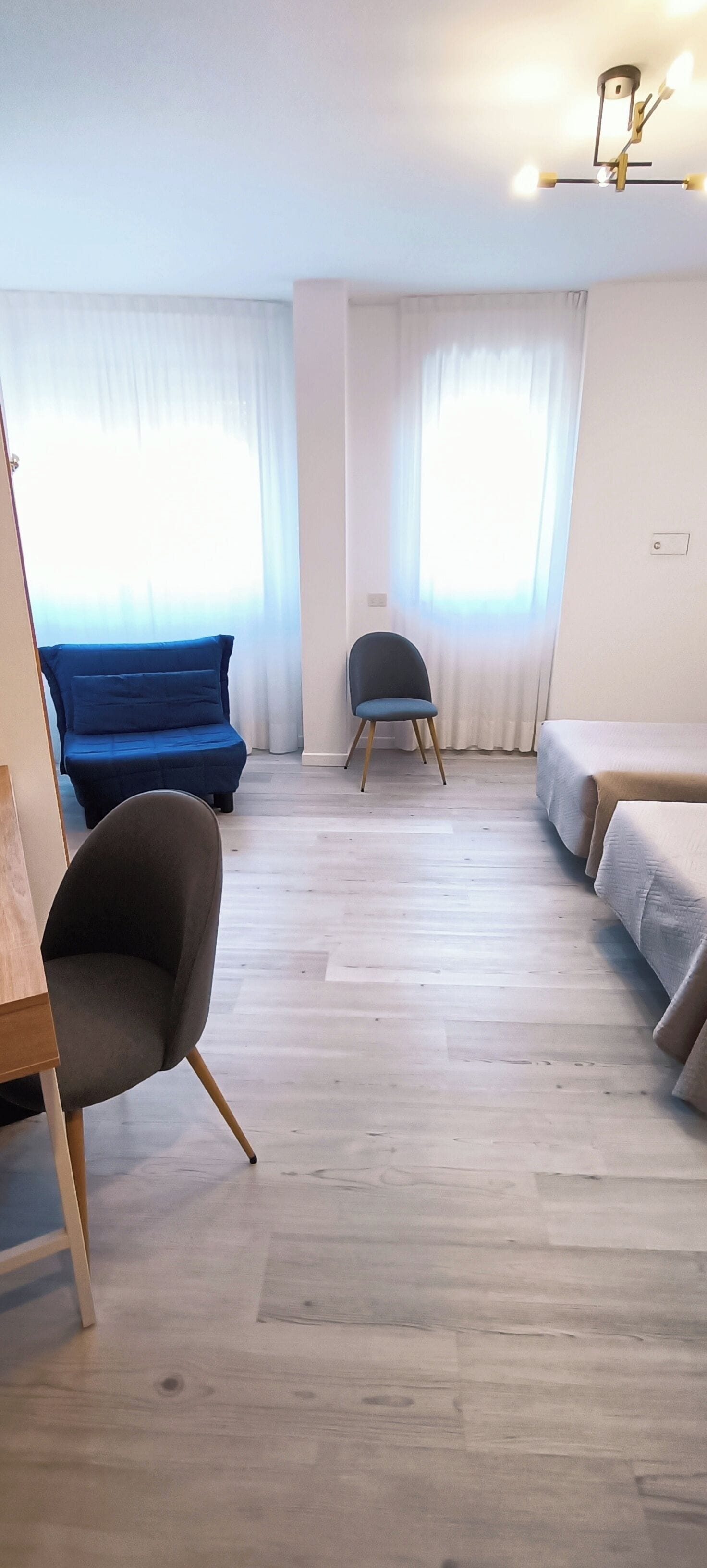 A modern room with a blue sofa, a grey armchair, and a bed.