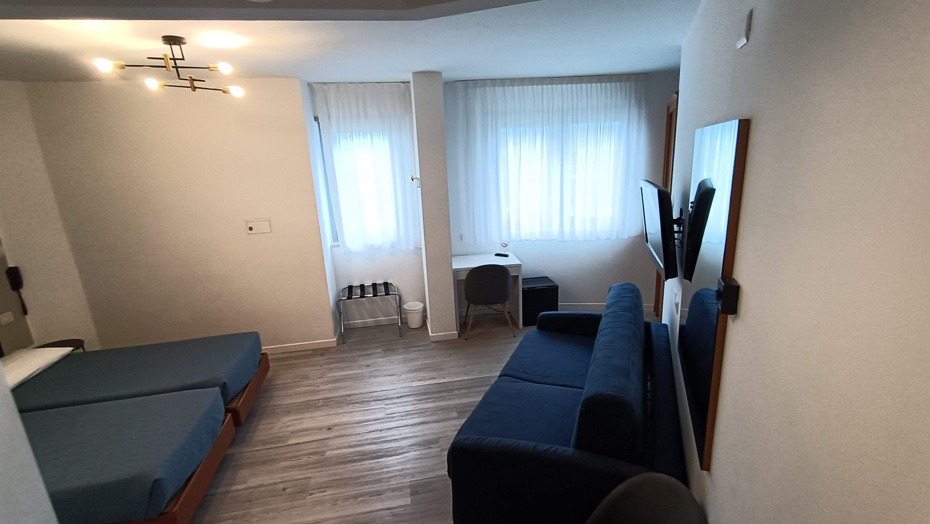 Una habitación con una cama, un sofá, un escritorio y una silla.