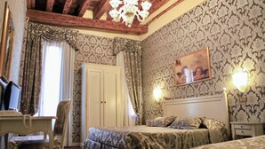 A bedroom with a bed, a desk, and a chair. There is a chandelier on the ceiling and a painting on the wall. - Hotel Bridge (Venice)