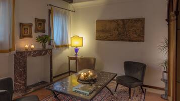 Una habitación acogedora con una chimenea de mármol, una mesa con velas y un cuadro grande en la pared.