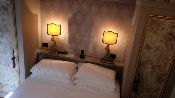 Una habitación de hotel con una cama grande, dos lámparas de noche y un espejo sobre la cama.
