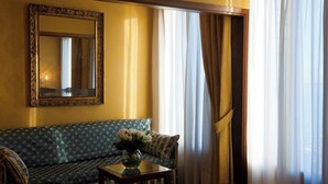 A room with a sofa, a table with a vase, a mirror, and curtains. - Pensione Wildner (Venice)