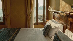A hotel room with a bed, curtains, a view of the water, and a balcony with a railing. - Pensione Wildner (Venice)