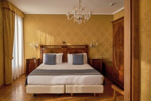 A hotel room with a large bed, wooden headboard, two bedside tables, a chandelier, and a wardrobe. - Pensione Wildner (Venice)