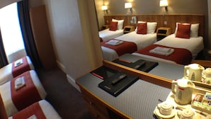 Une chambre d’hôtel avec deux lits, une table à manger avec un service à thé, et un grand miroir qui reflète la pièce.