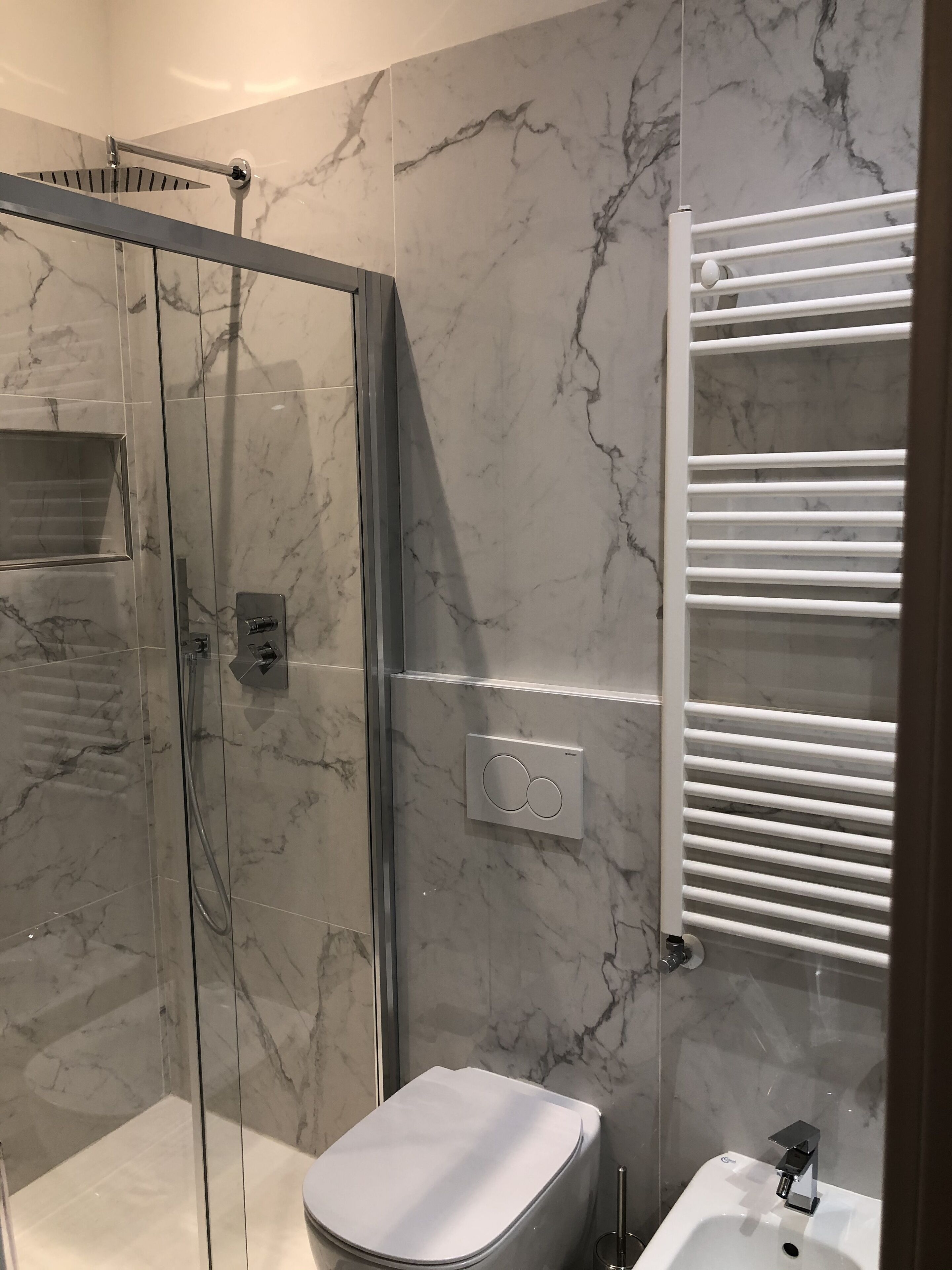 A bathroom with a glass-enclosed shower, a white toilet, and a built-in sink.