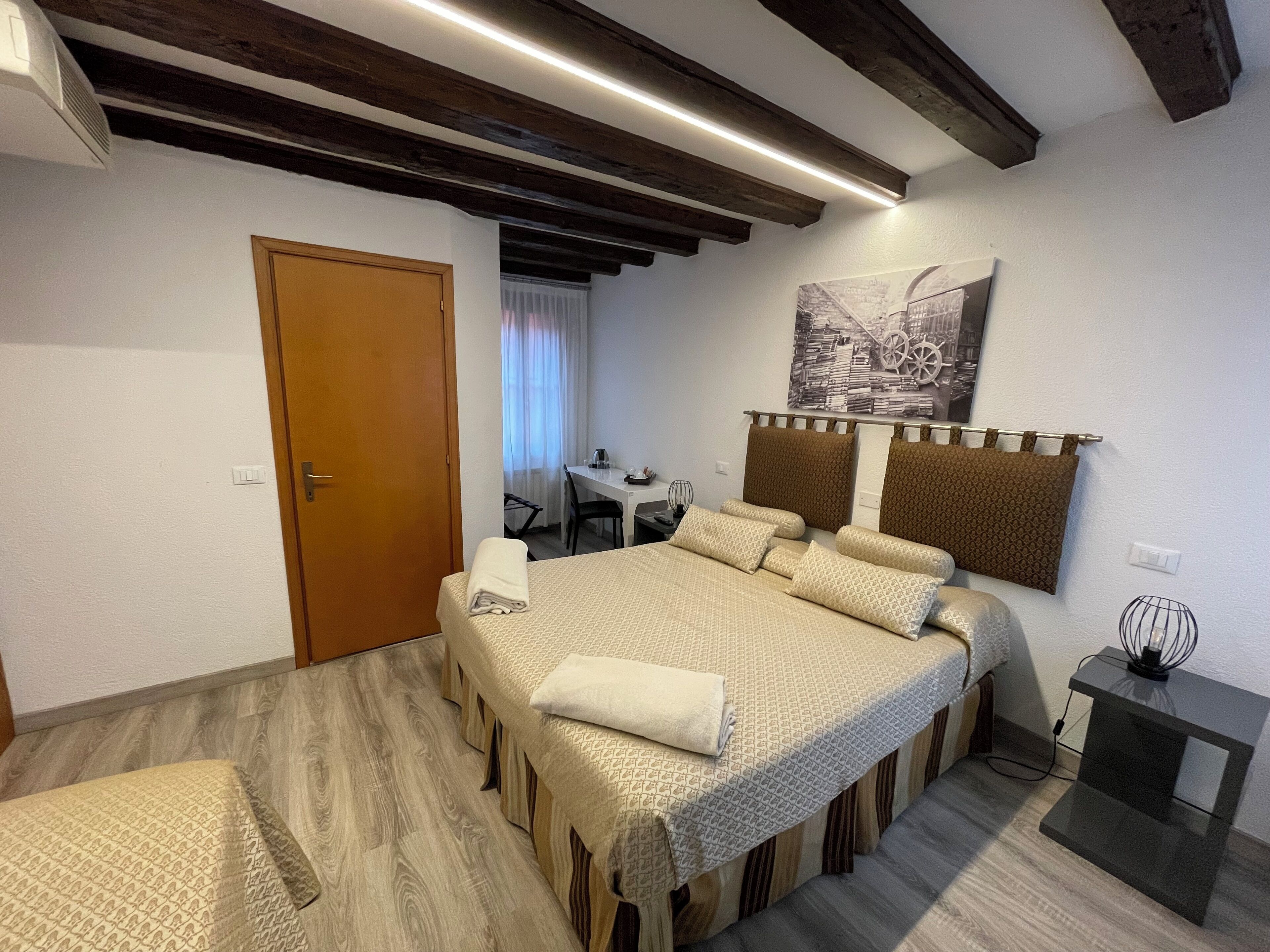 Una habitación de hotel con una cama grande, vigas de madera en el techo, un escritorio y una silla.