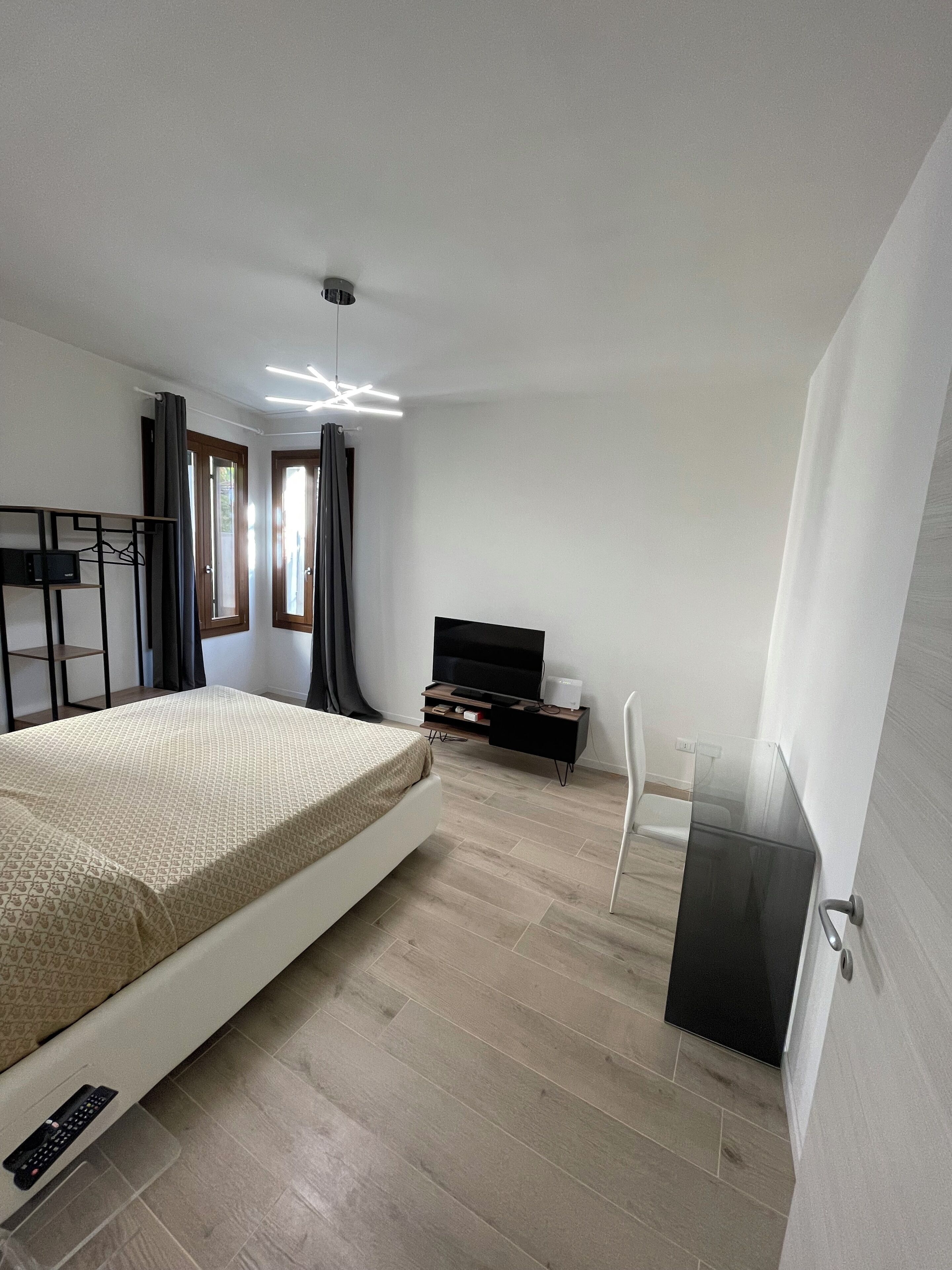 A modern bedroom with a bed, a TV, a desk, and a chair.