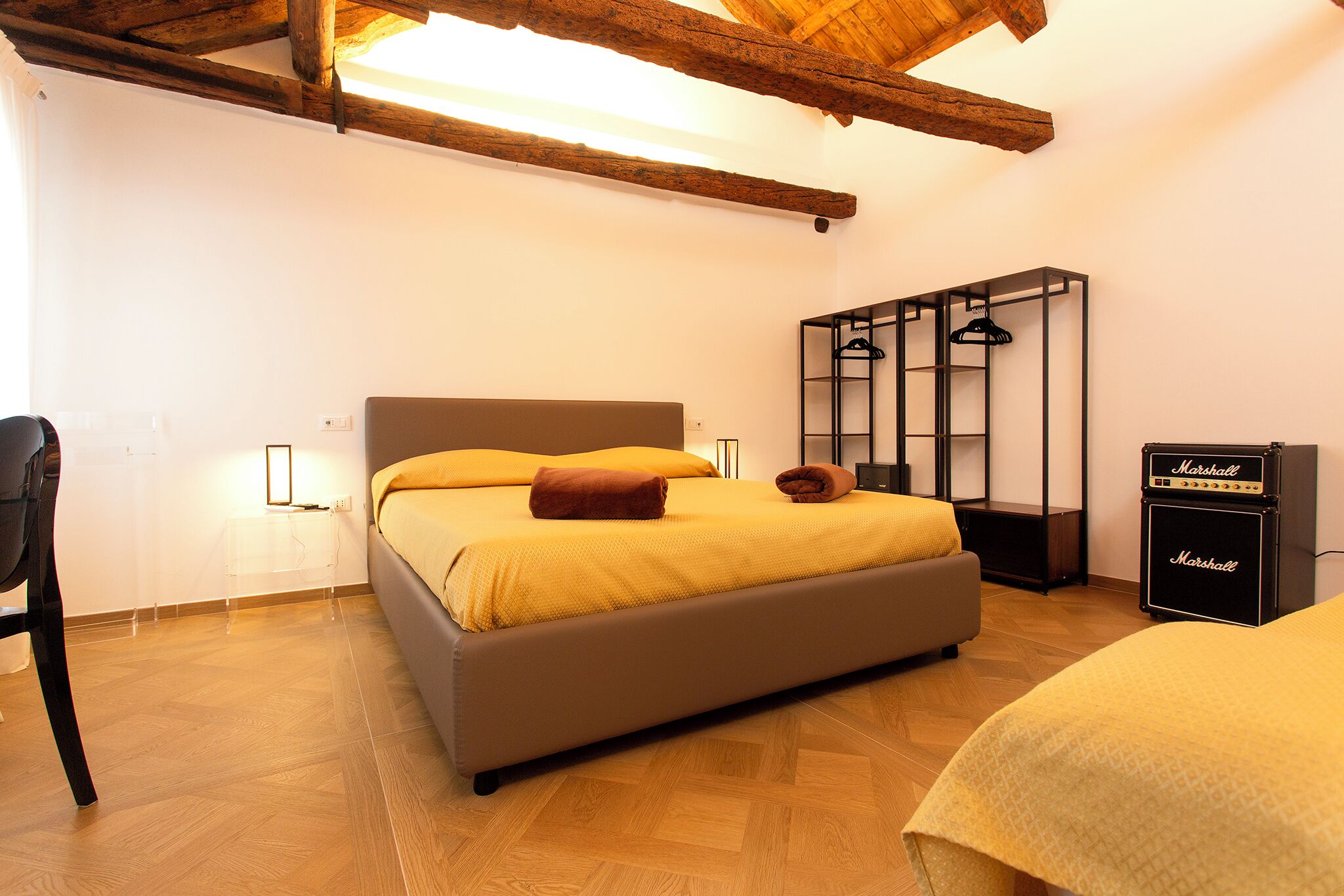 Une chambre à coucher avec un lit, une chaise, une armoire et un amplificateur Marshall.