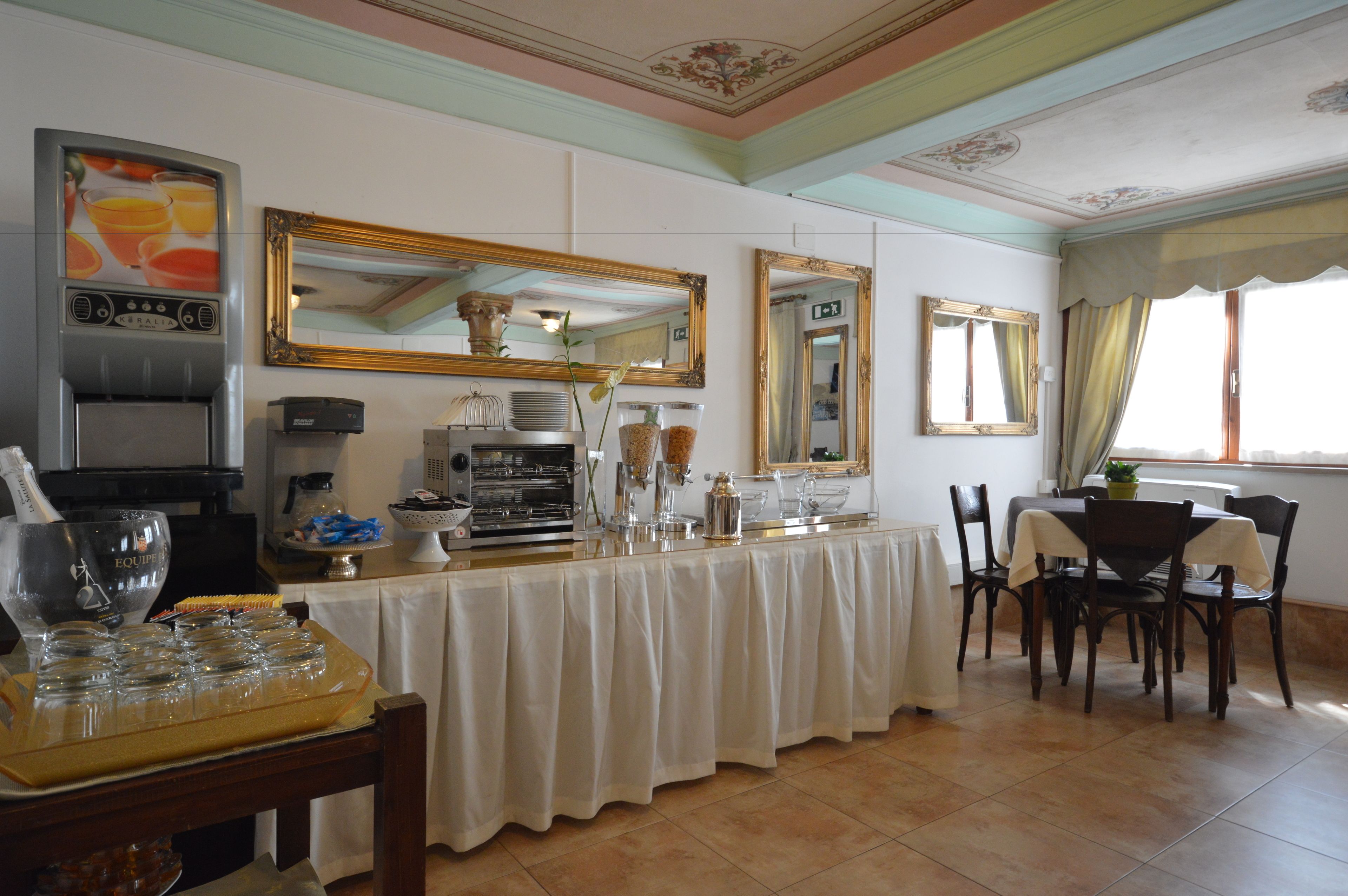 Un espace repas avec un buffet, comprenant une machine à café, des distributeurs de nourriture et un grand miroir.