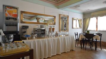 Un espace repas avec un buffet, comprenant une machine à café, des distributeurs de nourriture et un grand miroir.