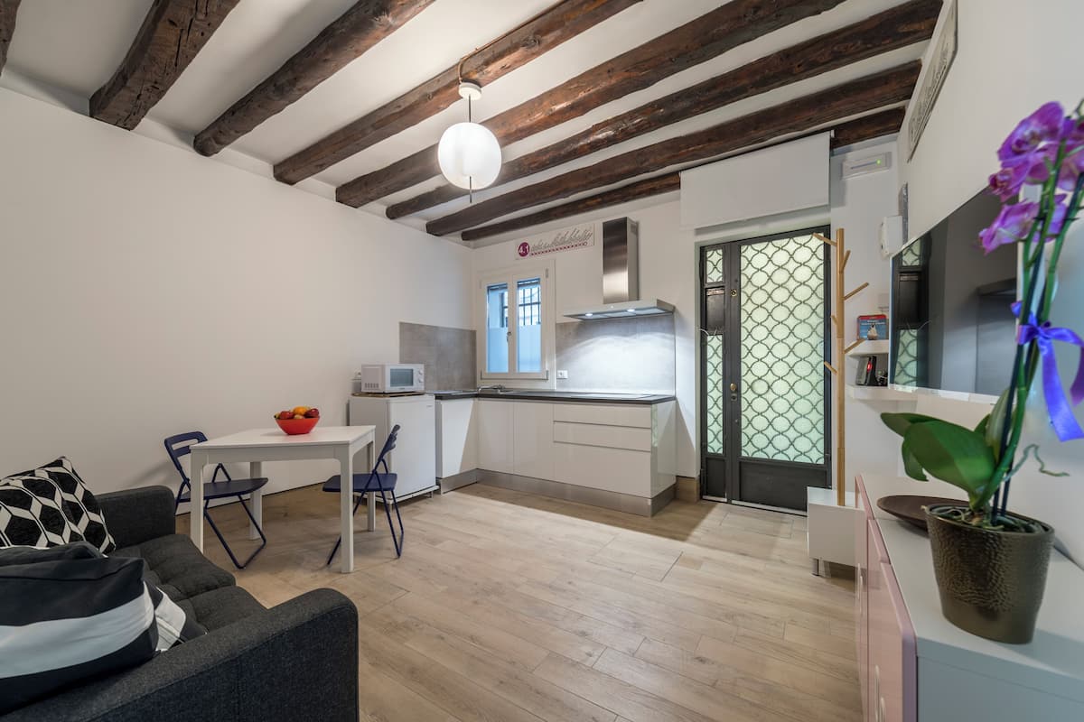 Una cocina moderna con armarios blancos, un microondas y una ventana con un diseño de cuadrícula verde.