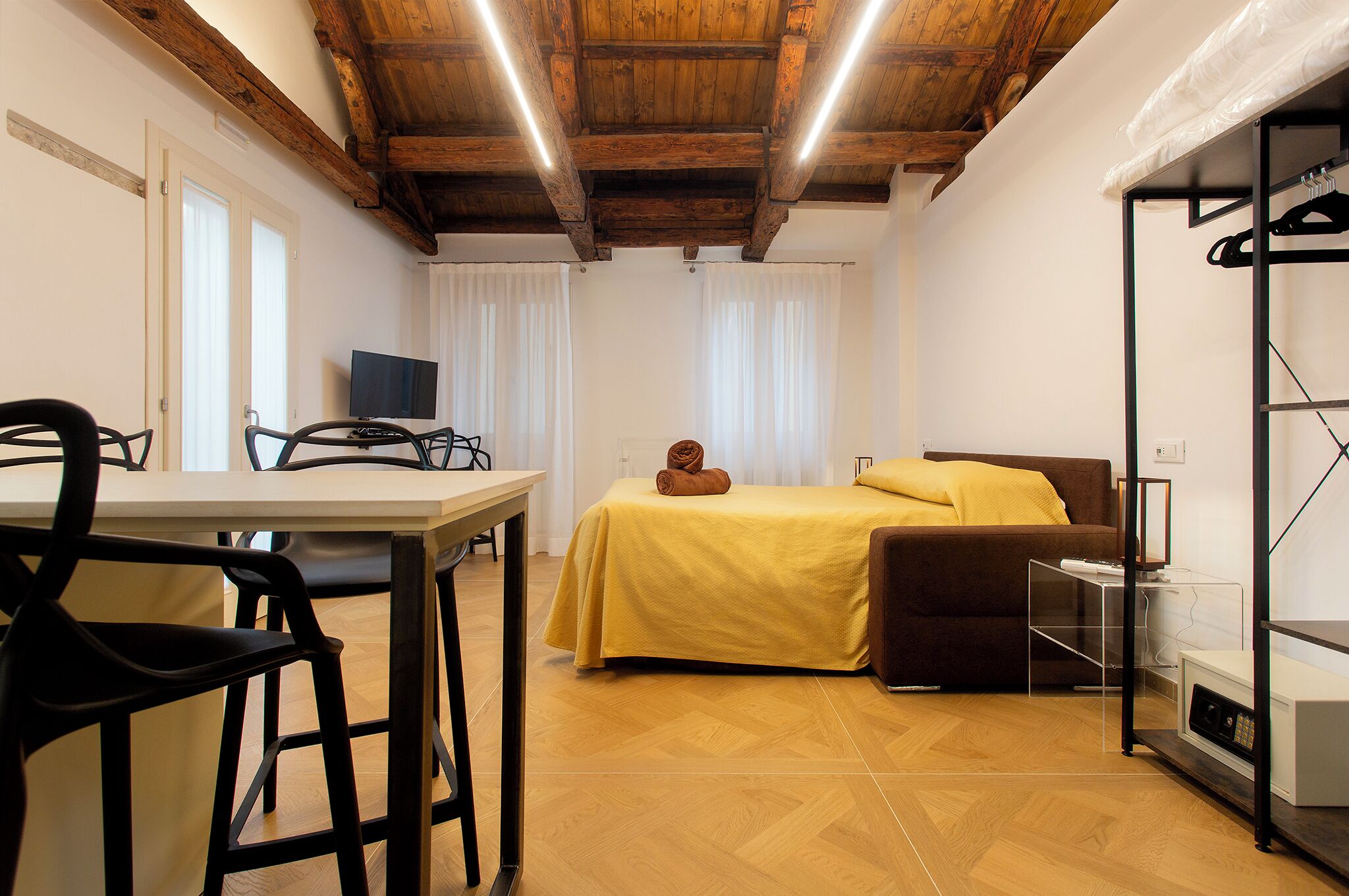 Ein Zimmer mit Bett, Tisch, Stühlen, Fernseher und Kleiderschrank.