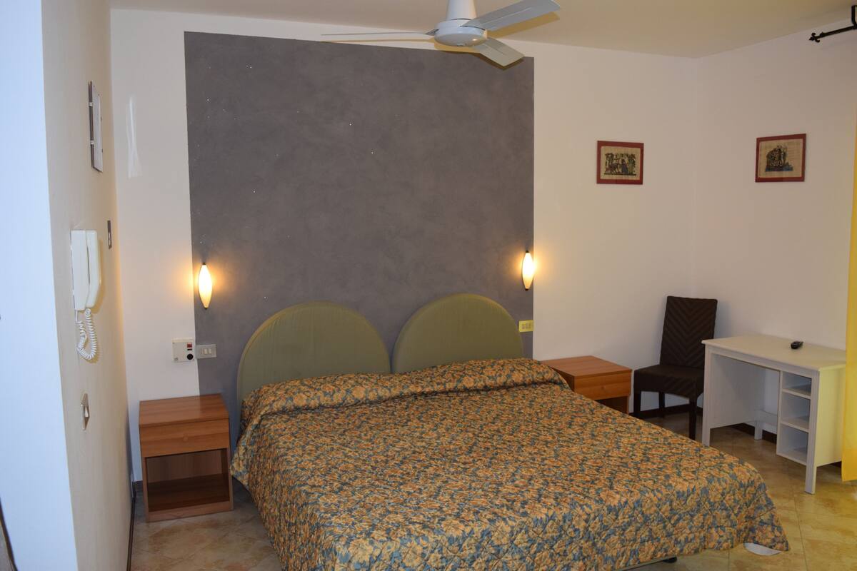 A bedroom with a bed, bedside tables, a desk, and a chair.