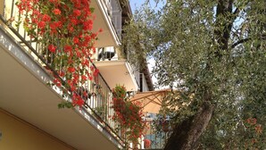 A building with balconies, a large tree, and a small garden area. - Casa Popi (Malcesine)