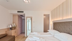 A hotel room with a large bed, a bedside table with a lamp, a wooden wardrobe, and a mirror. - Bellariva (Riva del Garda)