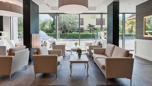 A modern lobby with a seating area, large windows, and a view of the outside. - Bellariva (Riva del Garda)