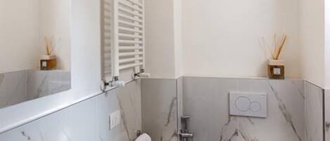 A modern bathroom with a marble sink, toilet, and shower.