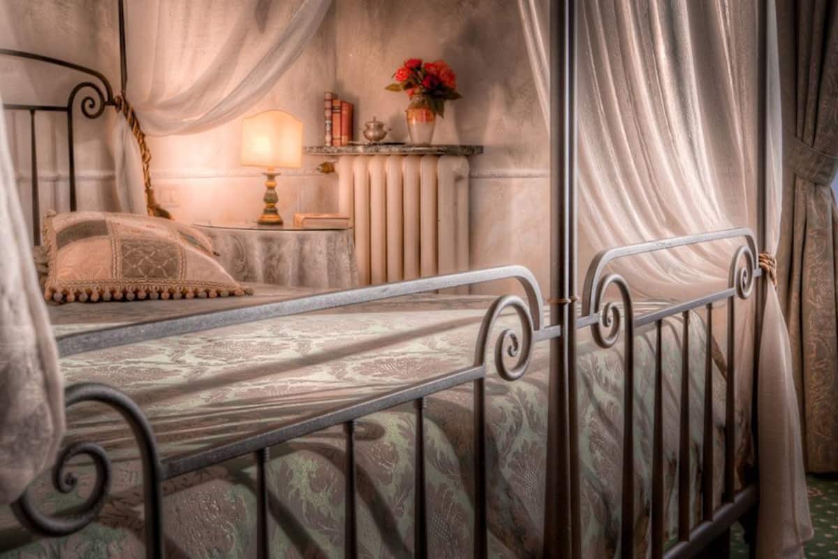 A bed with a metal frame, a bedside table with a lamp, and a radiator.