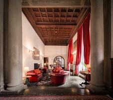 A grand lobby with a high wooden ceiling, large columns, red curtains, and a piano.