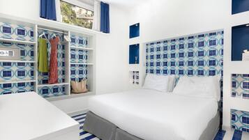 A hotel room with a bed, a wardrobe with hanging clothes, and a window with curtains.