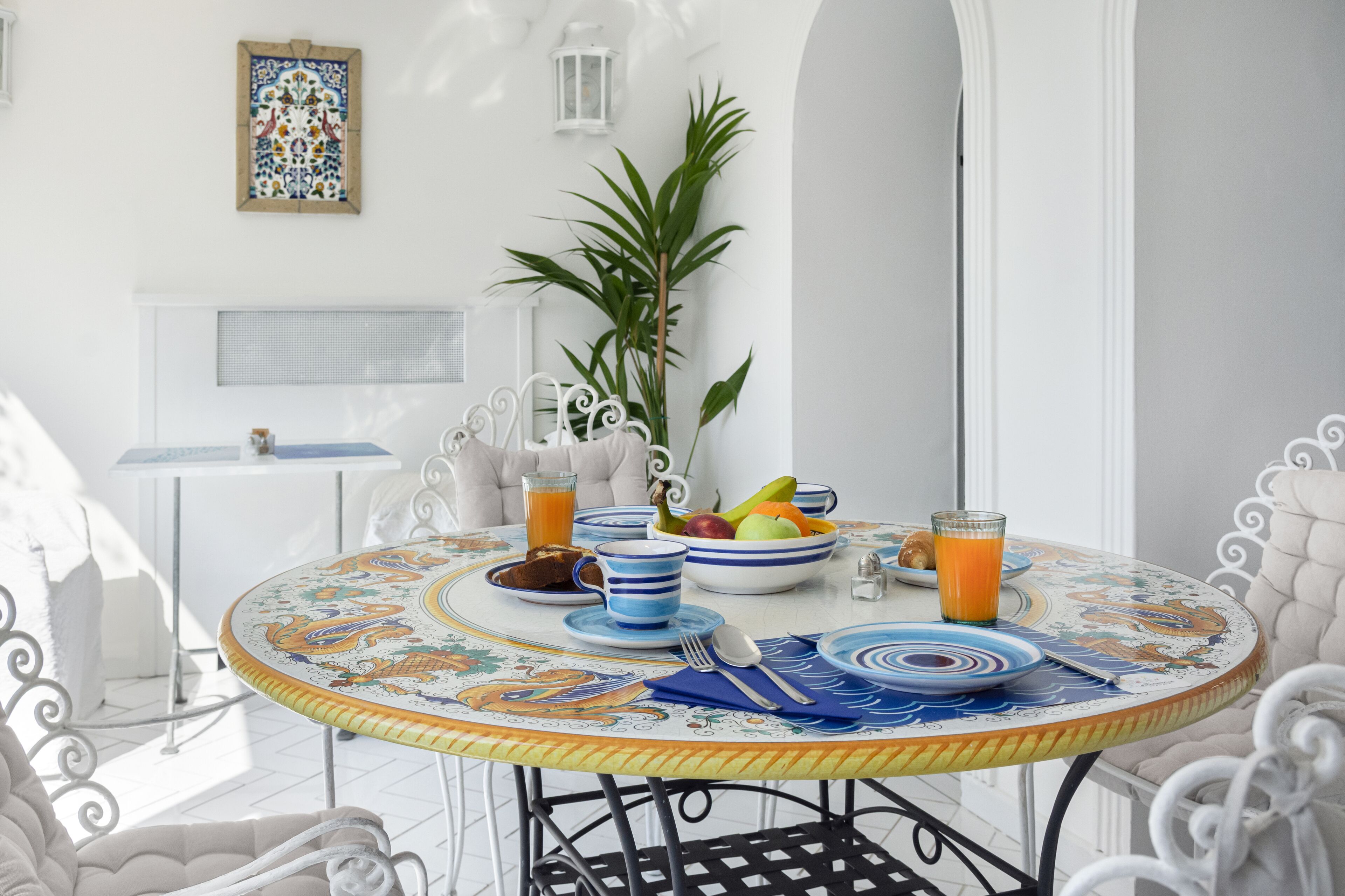 A round dining table with blue and white plates, a bowl of fruit, and a glass of orange juice.