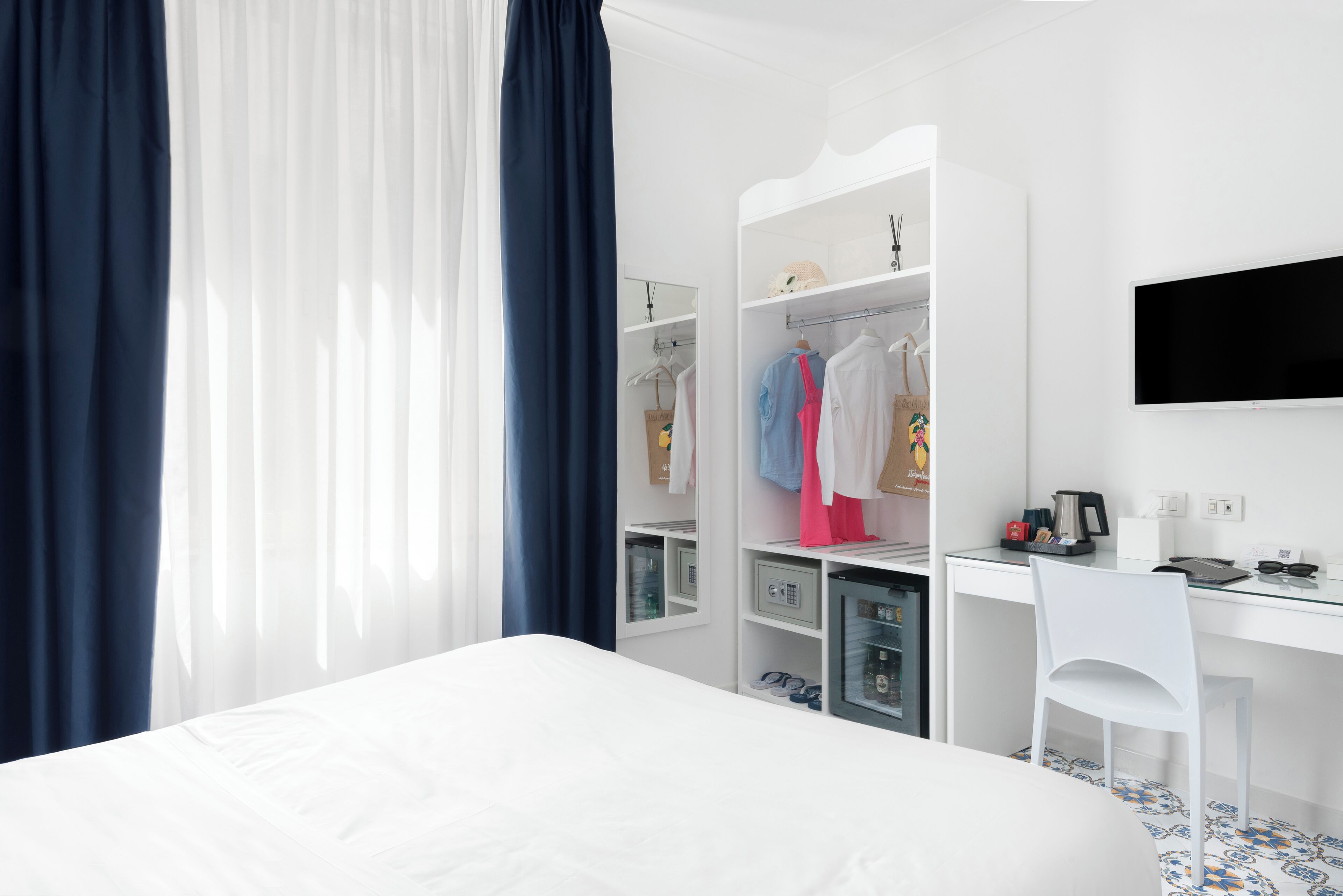 A hotel room with a bed, a desk, a chair, a wardrobe, and a television.