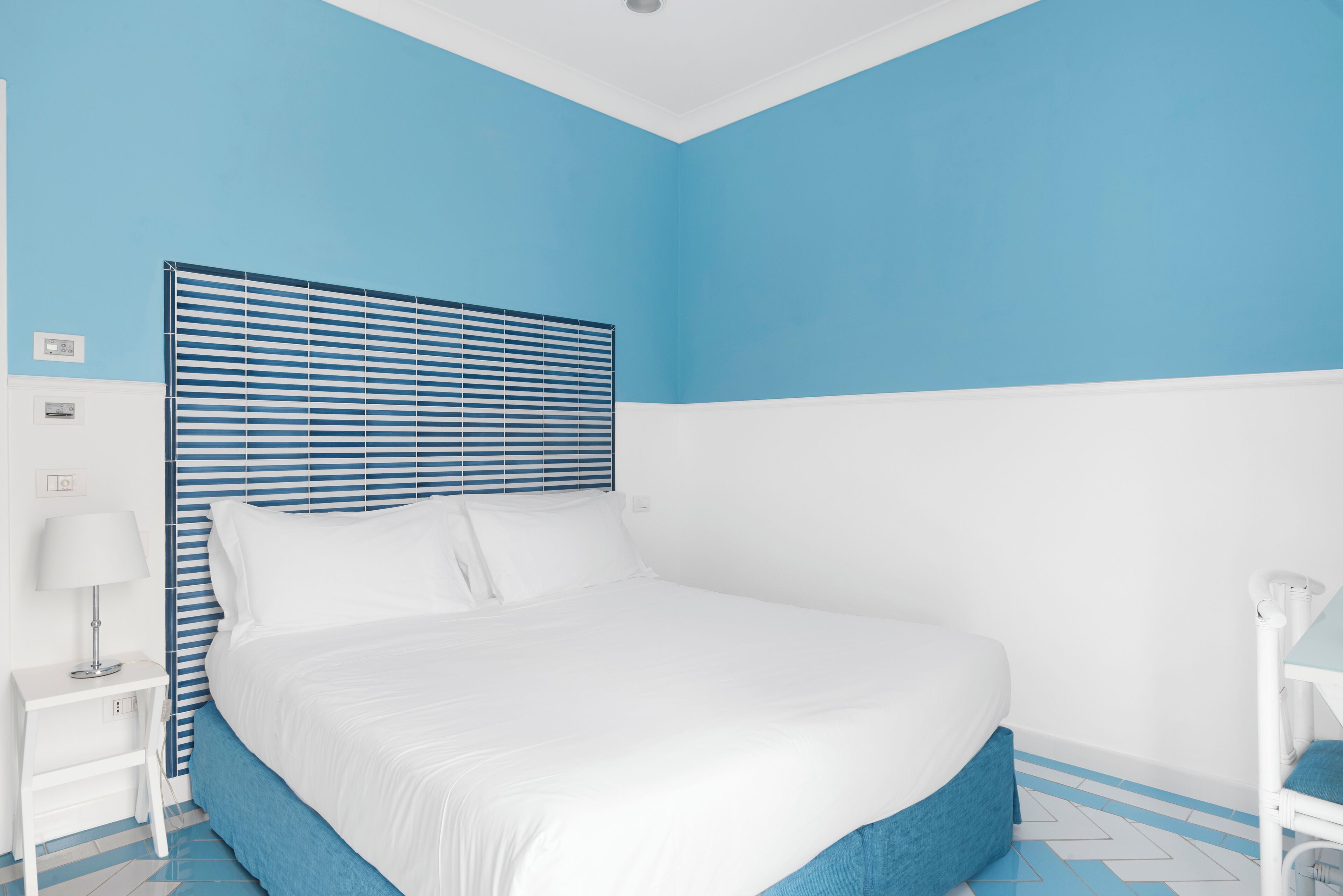 Une chambre à coucher avec un lit, une table de chevet, une lampe et une chaise.