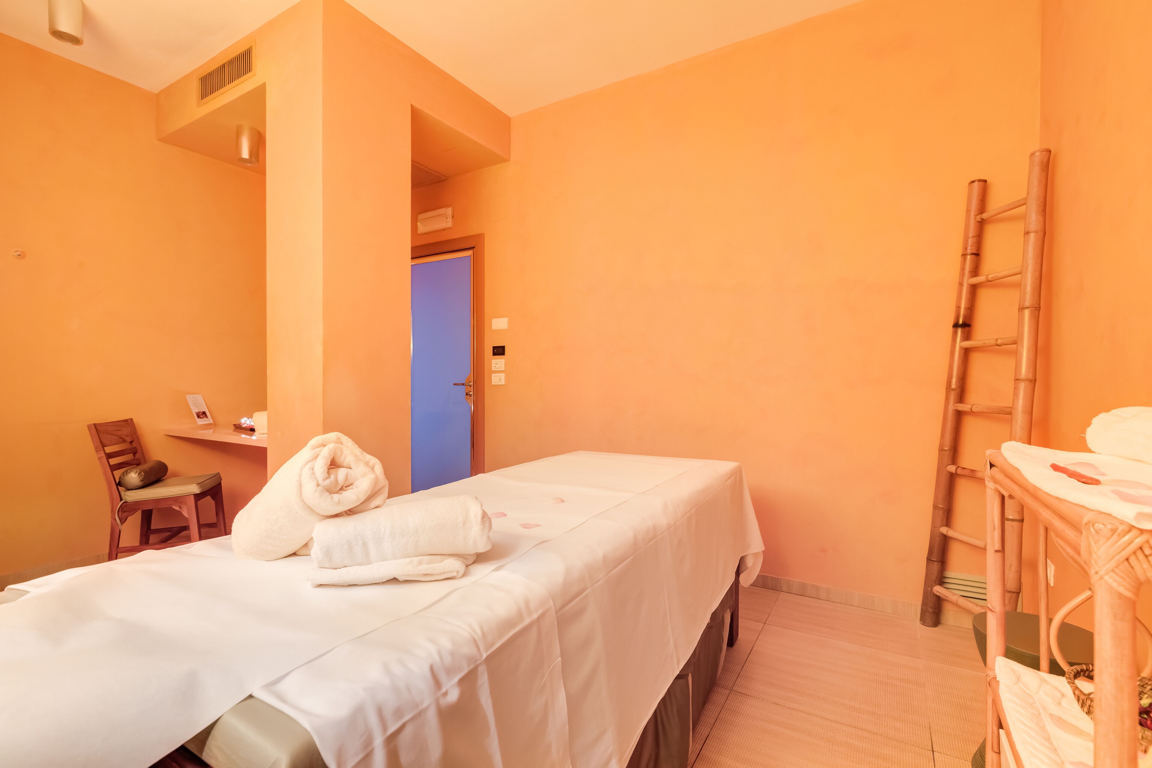 Una habitación con cama, una silla, un escritorio y una escalera.