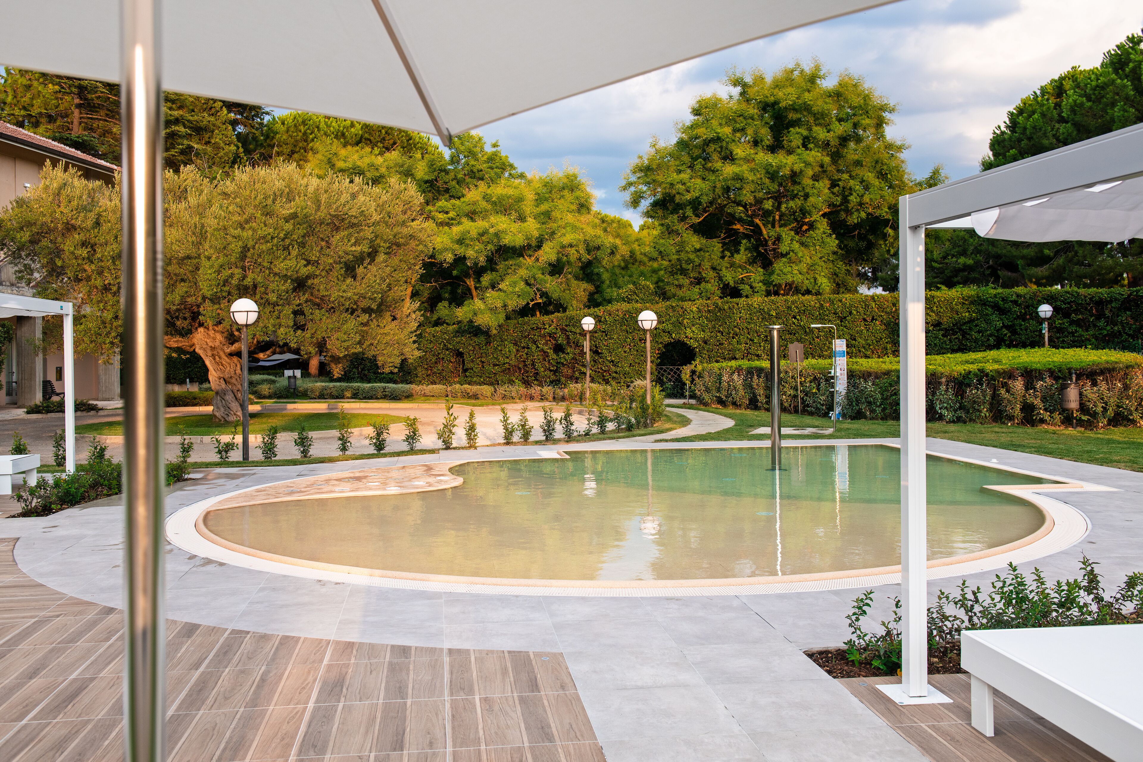 A circular pool with a curved edge, surrounded by a paved area with benches.