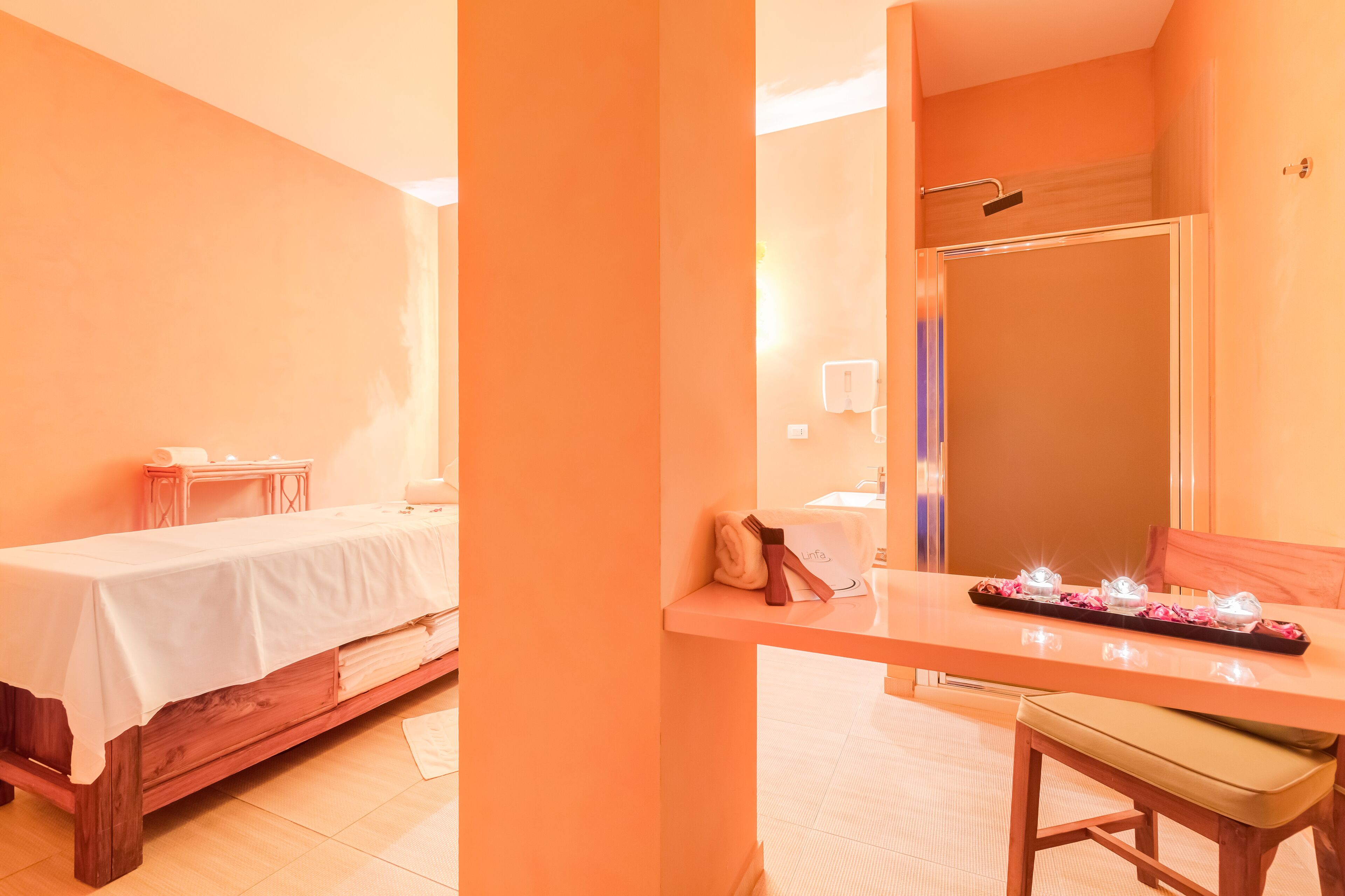 Quarto com cama, uma mesinha com artigos de higiene, uma cadeira e um espelho.
