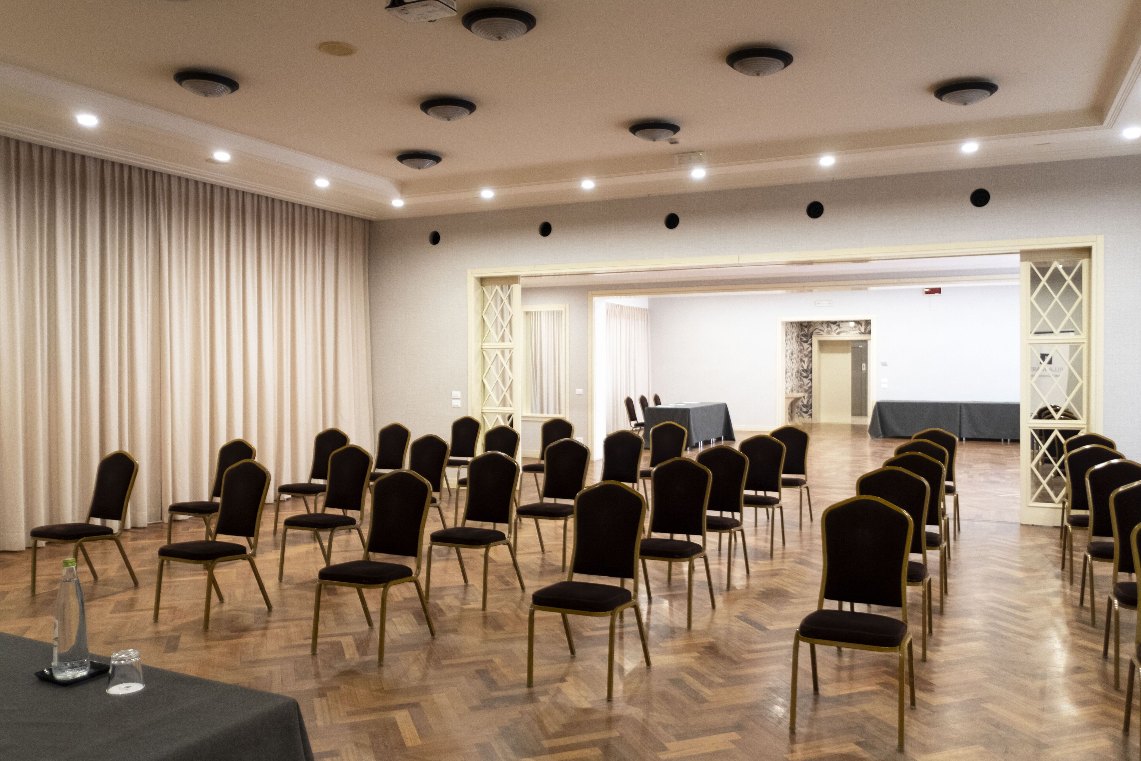 A conference room with rows of chairs, a table with a tablecloth, and a curtain on one side.