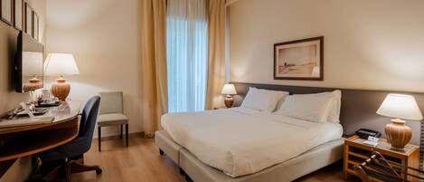 A hotel room with a bed, desk, chair, and bedside tables.