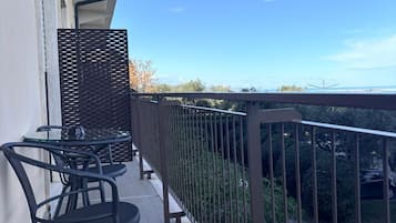 Un balcón con vista al mar, amueblado con una mesa y sillas.