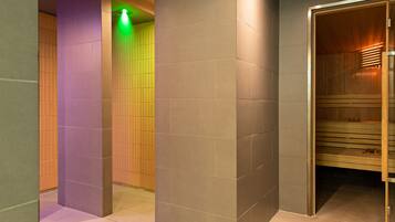 Un bagno moderno con sauna in legno, rivestimenti in piastrelle e porta in vetro.