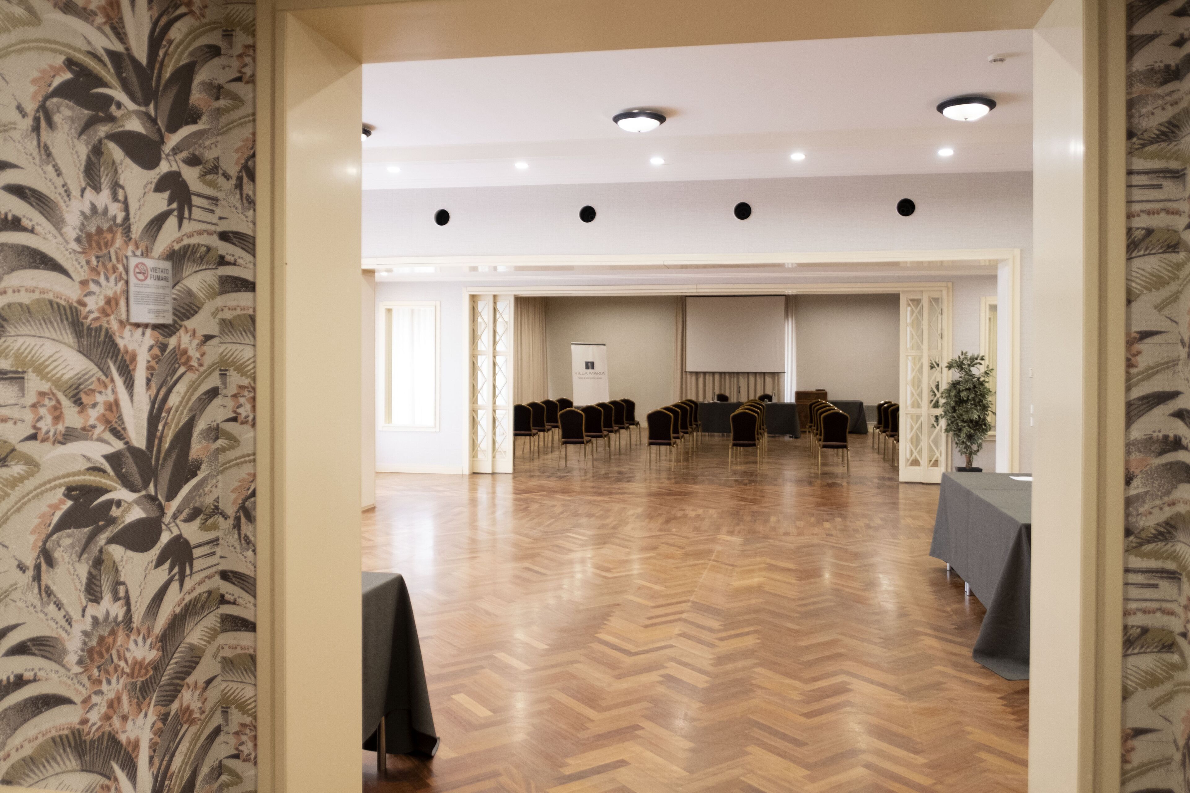 A conference room with a wooden floor, a whiteboard, and rows of chairs.