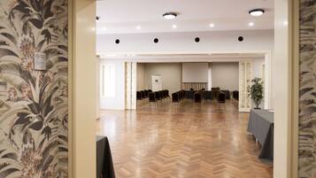A conference room with a wooden floor, a whiteboard, and rows of chairs.