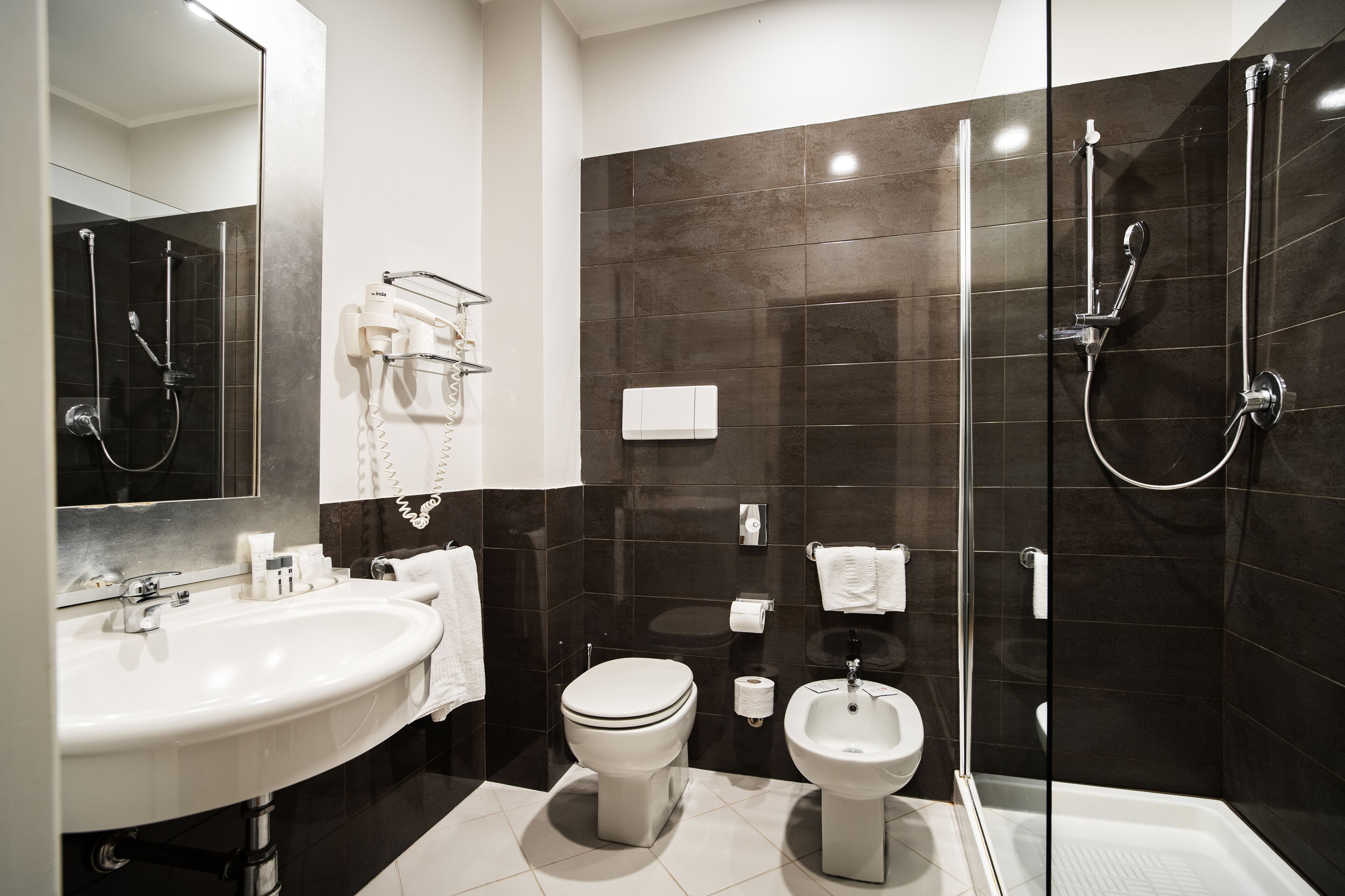 Ein modernes Badezimmer mit Waschbecken, Toilette, Bidet und Duschkabine.
