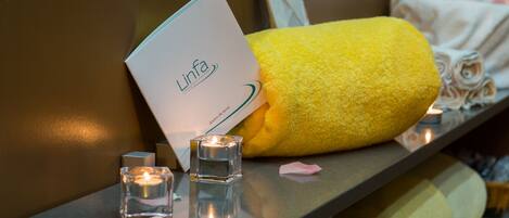 A spa setting with a yellow towel, a candle, and a card labeled "Linfa".