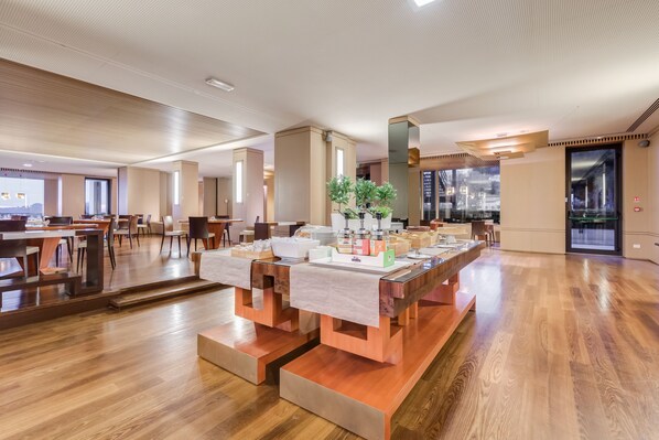 Un amplio vestíbulo de hotel con suelo de madera, muebles modernos y ventanas grandes que ofrecen vistas de la ciudad.