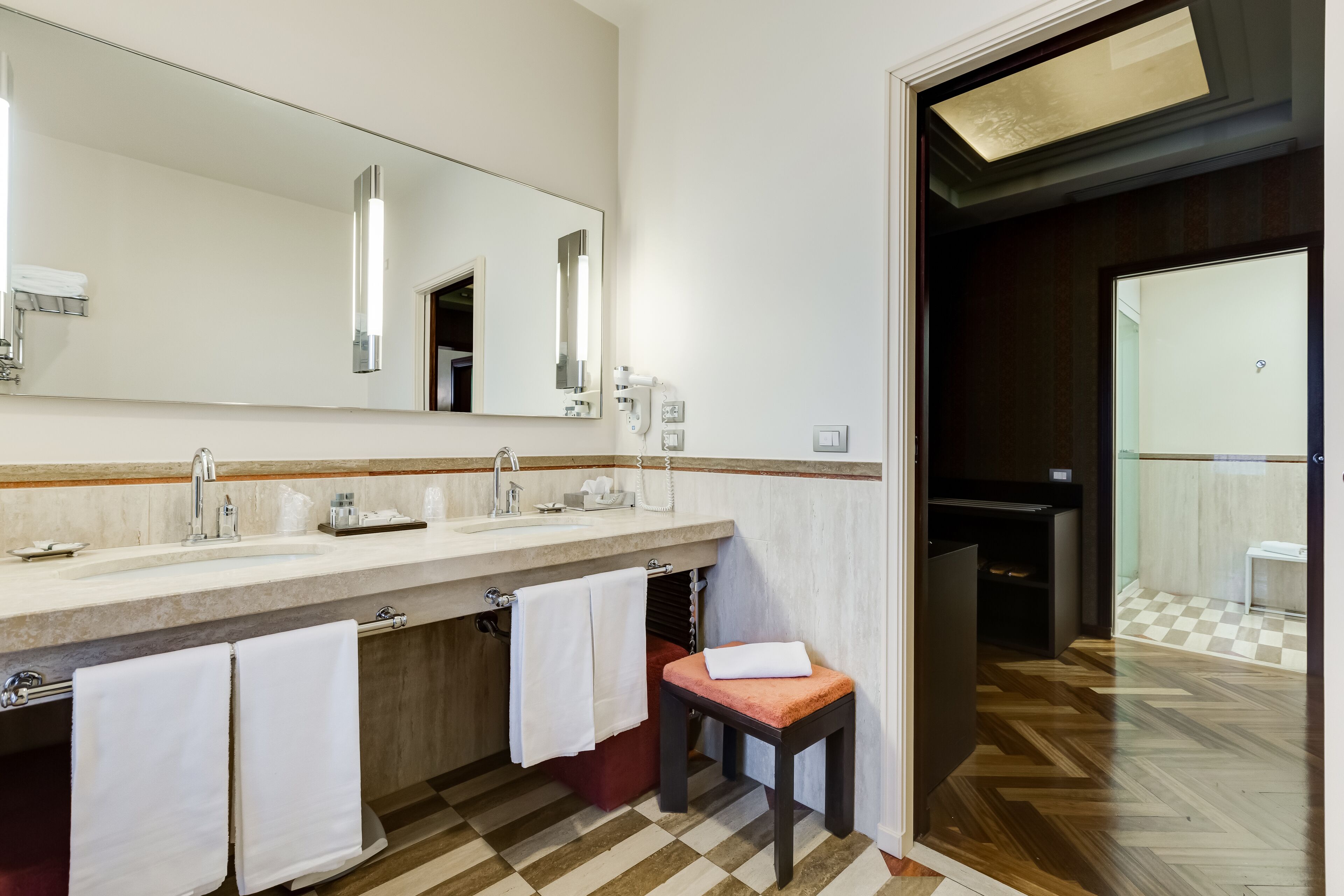 Une salle de bain moderne avec un grand miroir, deux vasques et un plancher en bois.