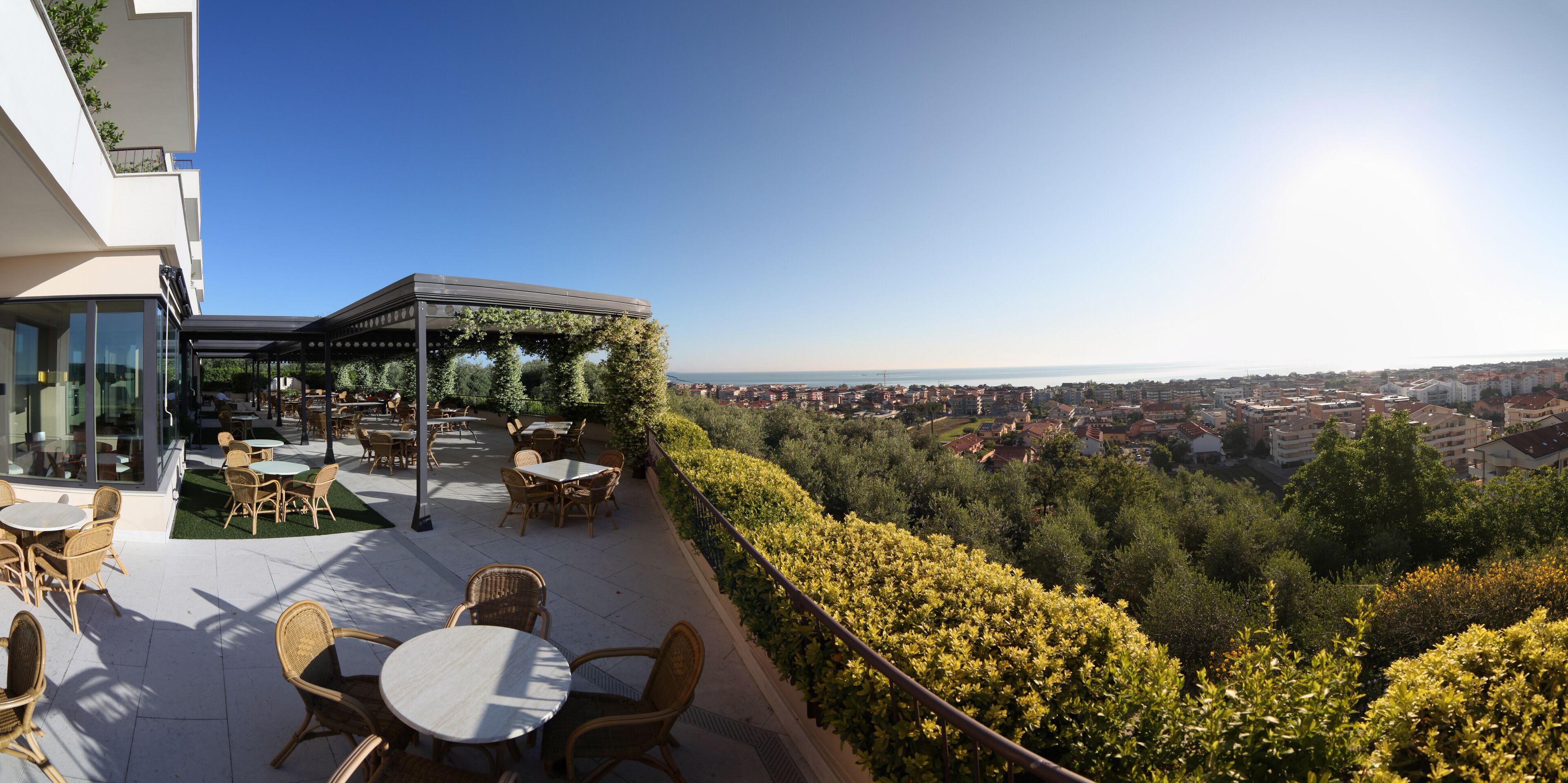 Terraza en la azotea con mobiliario exterior y vistas a un paisaje urbano.