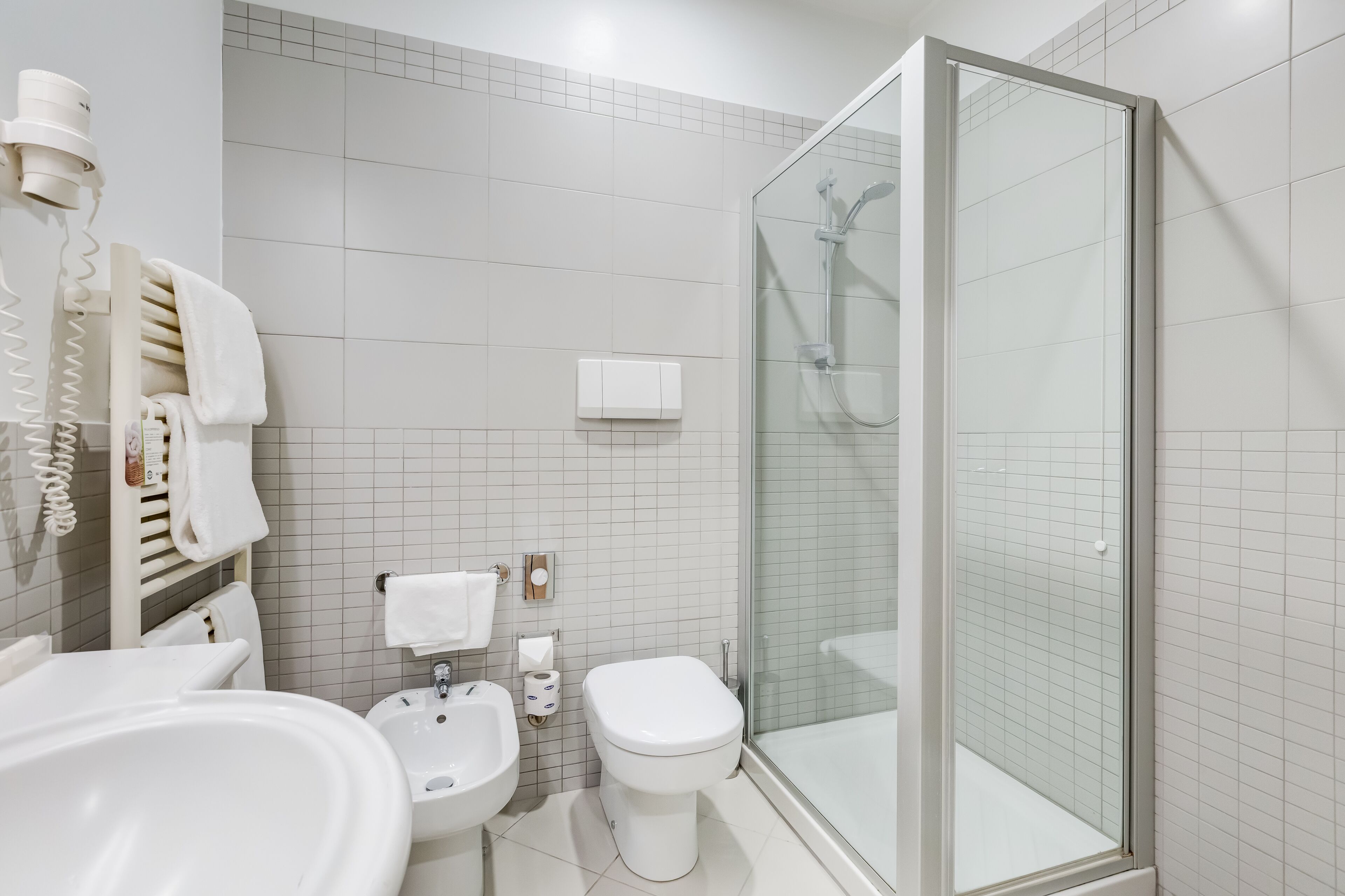 Une salle de bain moderne avec une douche à parois de verre, un lavabo, des toilettes et un porte-serviettes.